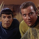 Spock and Captain Kirk hide among some reeds.